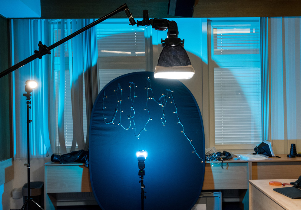 Studio setup with string lights on a dark backdrop, an overhead softbox and separate flash units
