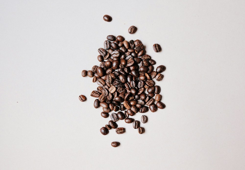 Pile of brown coffee beans on a pale surface