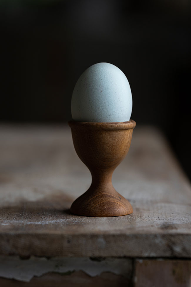 Egg in a wooden cup, with a bright right side and shaded left side